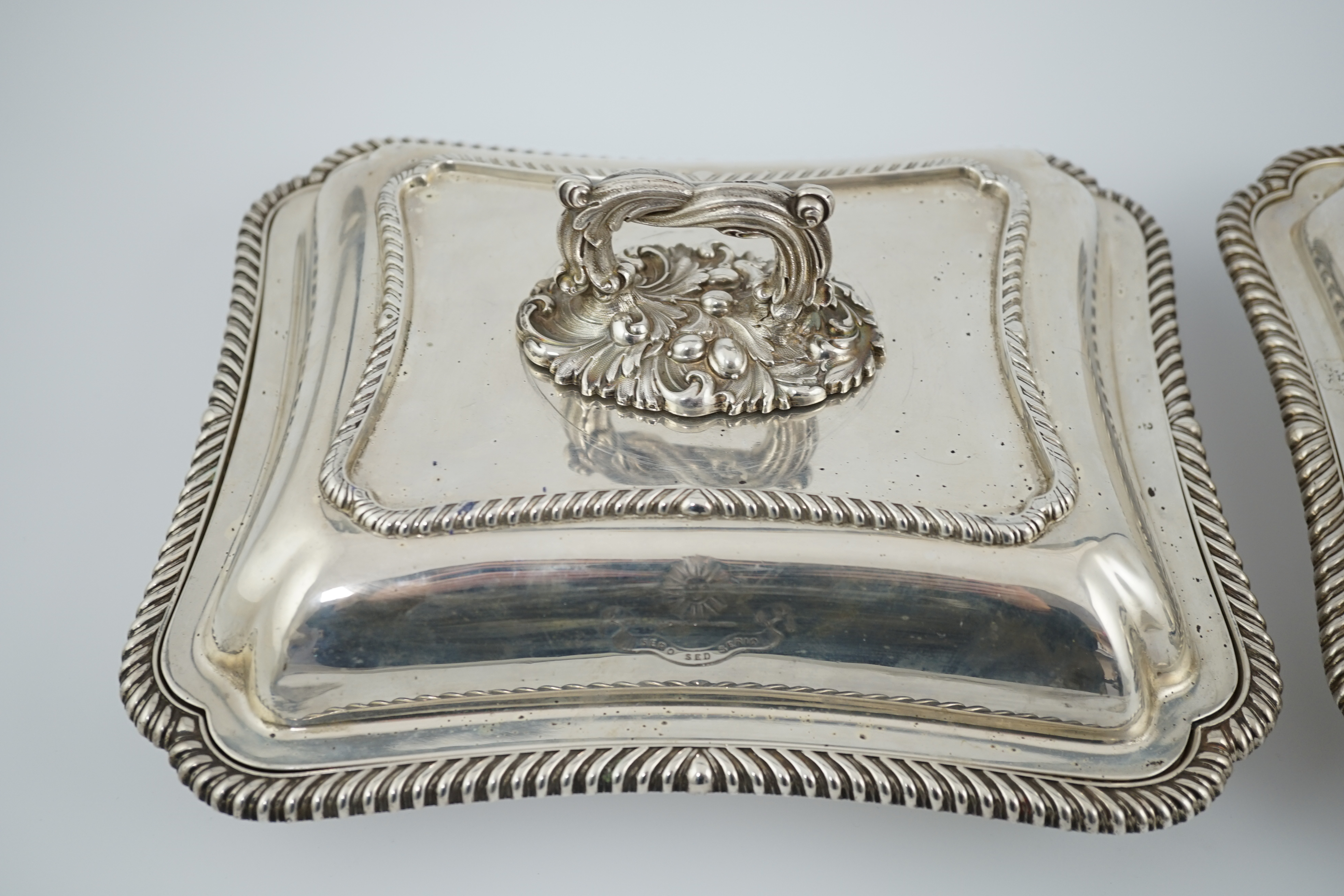 A pair of Edwardian silver shaped rectangular entrée dishes and covers with handles, by Goldsmiths & Silversmiths Co Ltd